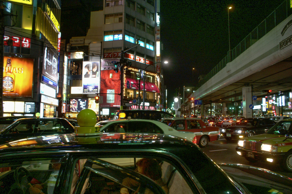 Lots of taxis and buildings with neon signs